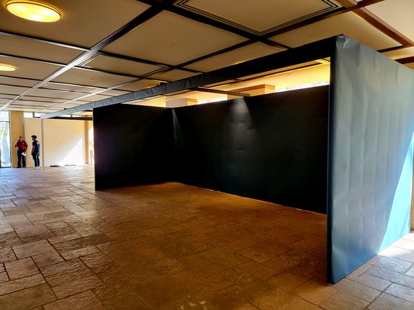 Charcoal-black temporary booth walls with a cyan side panel on a stone tile floor under a coffered ceiling, Omaha 2023