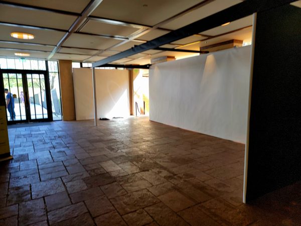 White temporary partition walls with a black top rail on a stone tile floor beside glass doors, Omaha 2023